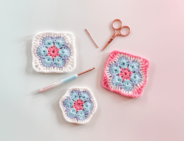 3 African Flower granny squares on an ombre background as a flat lay with scissors a needle and a hook.