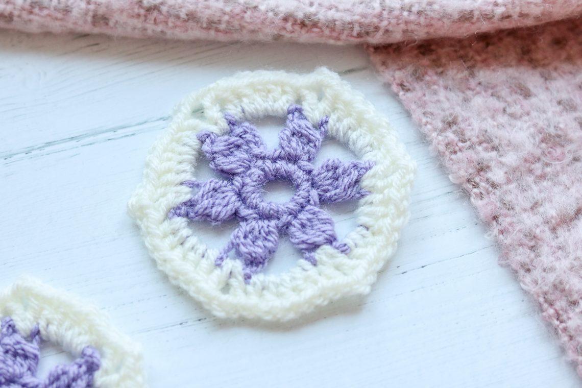 Flower hexagon crochet on a white background with some pink crochet.