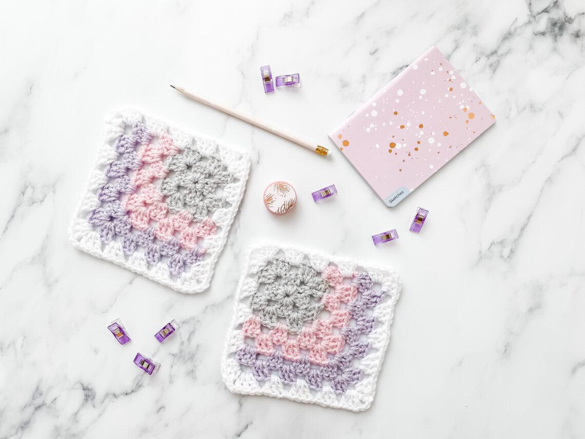 Mitered granny square on a marble background with stationery.