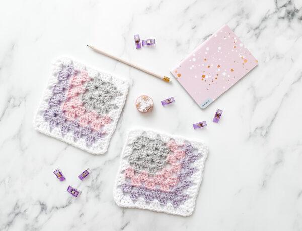 Mitered granny square on a marble background with stationery.