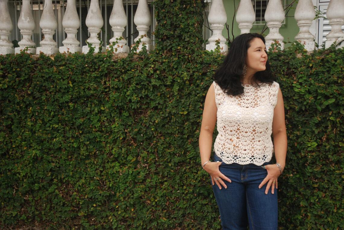 women wearing a cream crochet top stood in front of a hedge