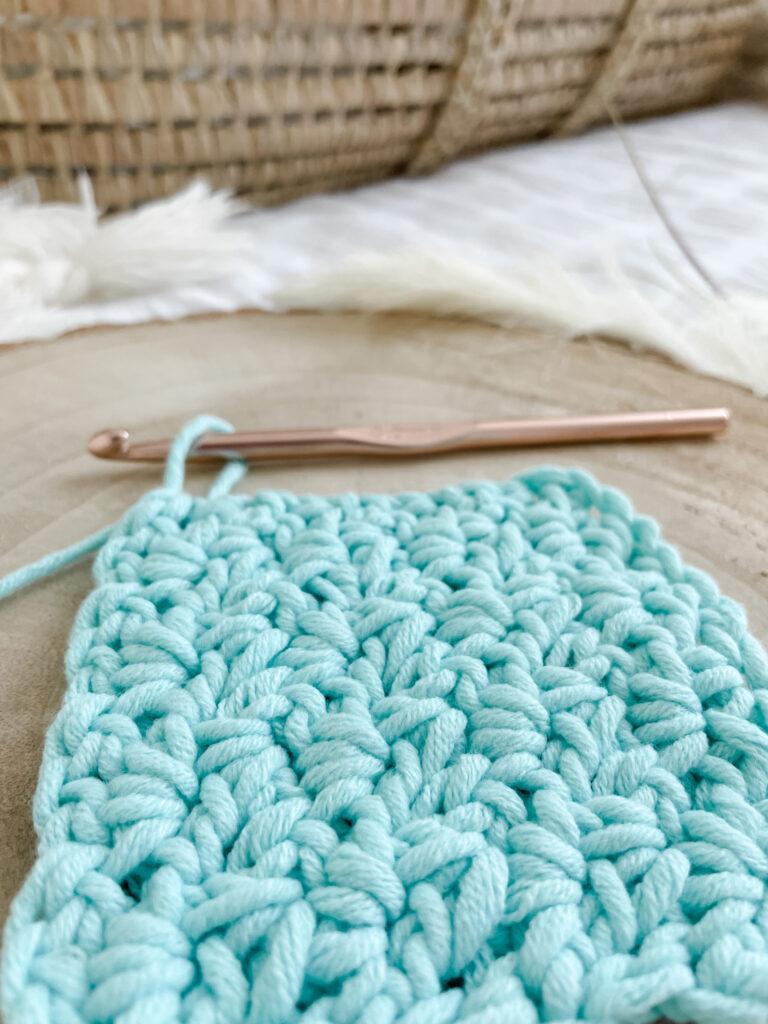A swatch of wattle stitch in progress is shown using bright aqua yarn. 