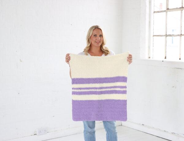 Switch It Up Blanket held by Sarah-Jayne in a white room.