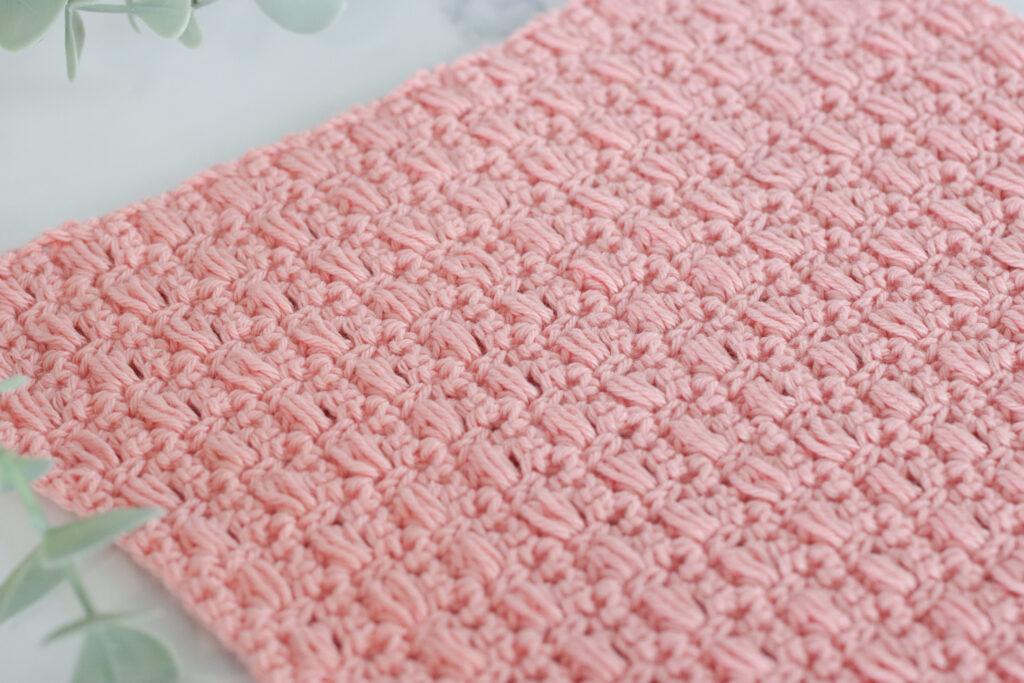 Reverse side of a pink crochet swatch using the blocked bead stitch, showing textured stitch definition