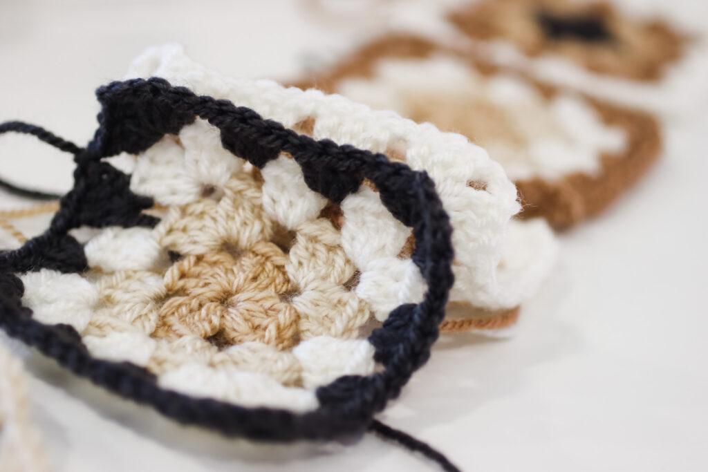 behind the scenes image of the not the high street poncho being designed featuring granny square samples 