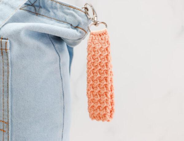 Keychain on a denim bag made from orange crochet on silver hardware.