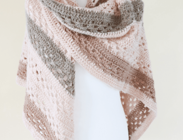 Crochet shawl on a white mannequin in peach, grey and brown yarn.